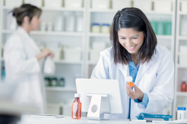 Female Pharmacist Uses Computer In Pharmacy