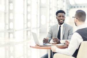 Alt text: Smiling Black man meeting with a colleague.