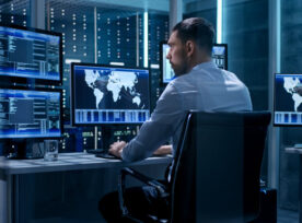 Technical Controller Working at His Workstation with Multiple Displays. Displays Show Various Technical Information. He's Alone in System Control Center.