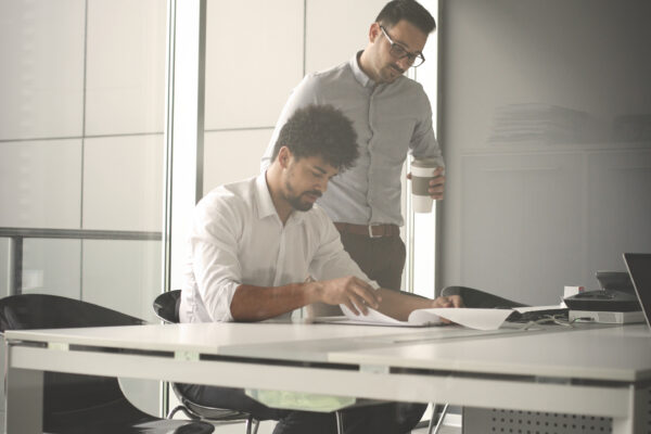 Two Business Men Working Together In Office. Reading Document.