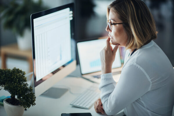 Woman sits at desk reviewing product data before entering it into a PIM.