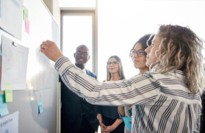 Coworkers Strategizing Together On A Whiteboard In An Office