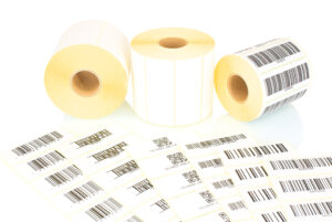 White Label Rolls And Printed Barcodes Isolated On White Background With Shadow Reflection. White Reels Of Labels For Printers. Labels For Direct Thermal Or Thermal Transfer Printing. Barcode Samples.