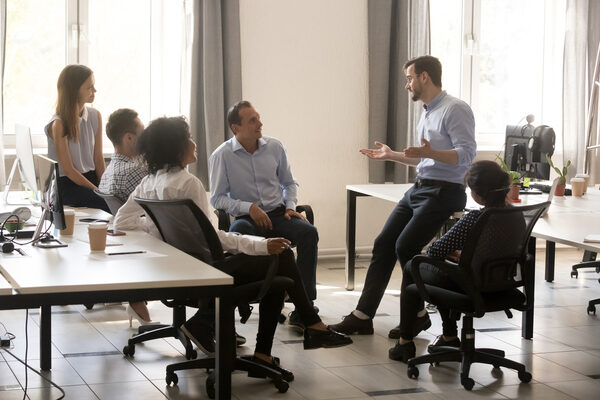 Male Team Leader Talking To Diverse Businesspeople At Office Meeting