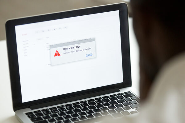African Man Using Laptop With Application Failure Message On Screen