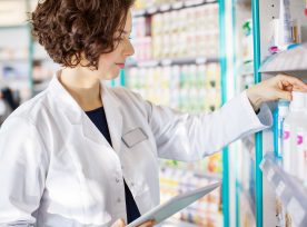 Young Pharmacist With A Tablet In Drug Store