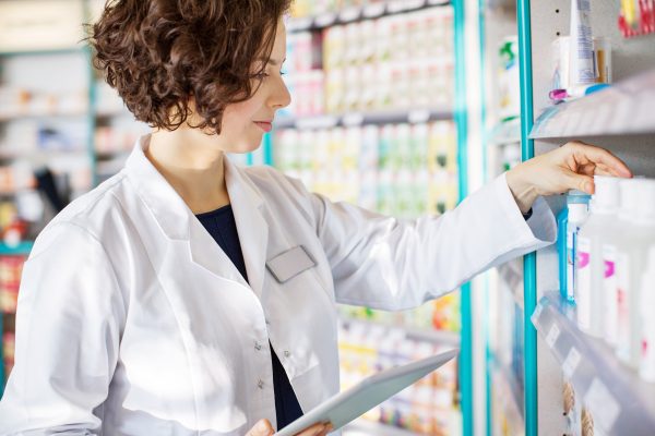 Young Pharmacist With A Tablet In Drug Store