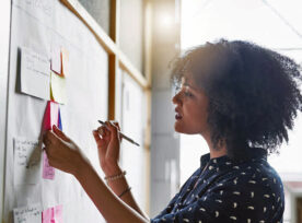 Photo: Woman is planning with post-it notes and markings at a whiteboard.