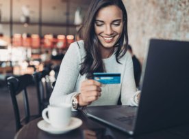 Woman Looking At Her Credit Card At Computer and Smiles