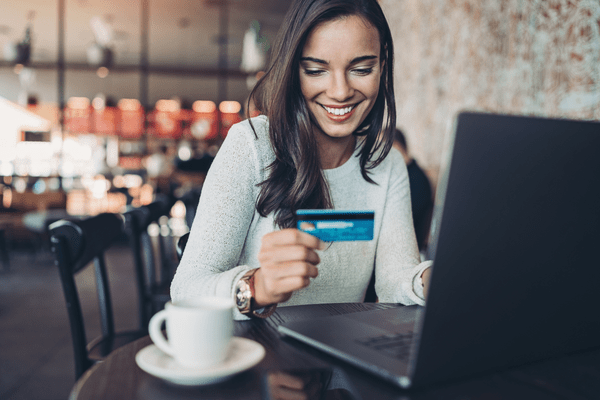 Woman Looking At Her Credit Card At Computer and Smiles