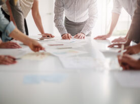 Low Angle View Of Hands Of Multiracial Group Of People Working With Ideas And Brainstorming Together To Make Decisions With Documents On Table In Creative Office Teamwork