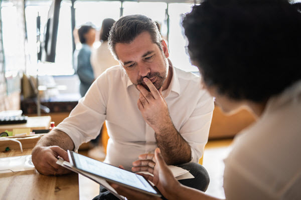 Man looking at tablet with coworker